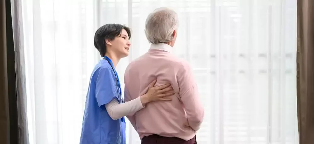 Fisioterapeuta e paciente idoso em frente à janela