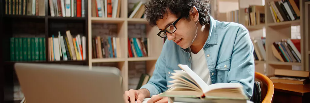 Rapaz estudante lendo livros em biblioteca
