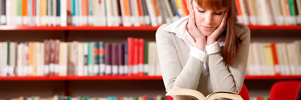 Moça lendo livro em biblioteca