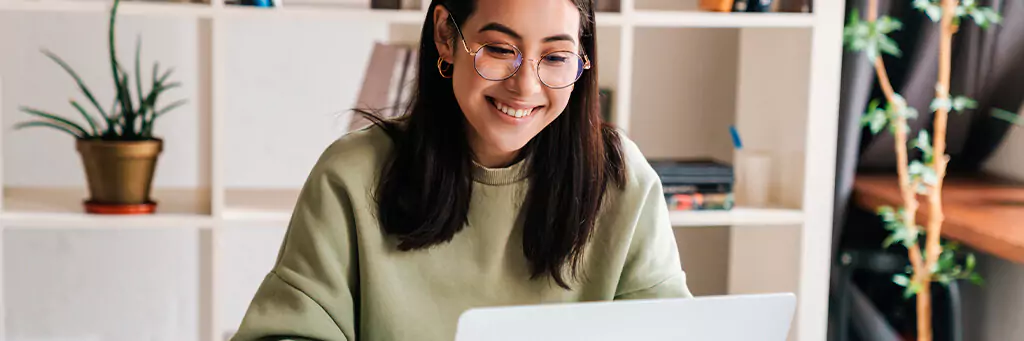 Moça sorrindo e olhando para laptop