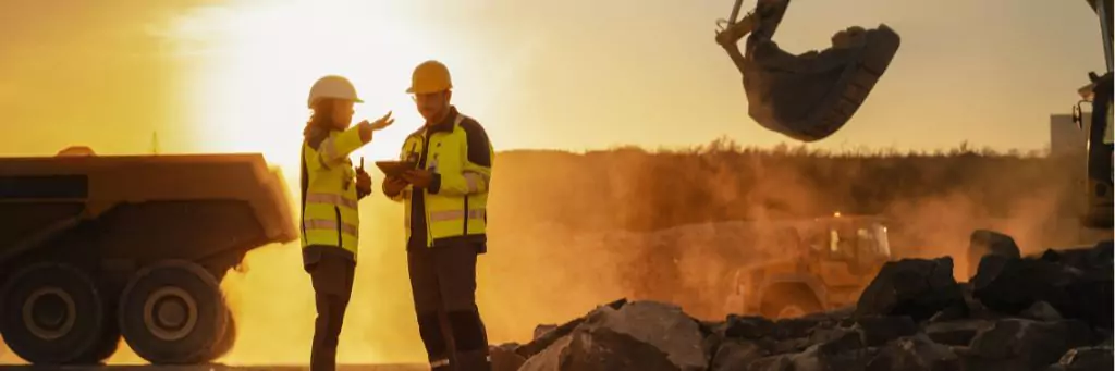 engenheira e engenheiro em obra ao pôr do sol