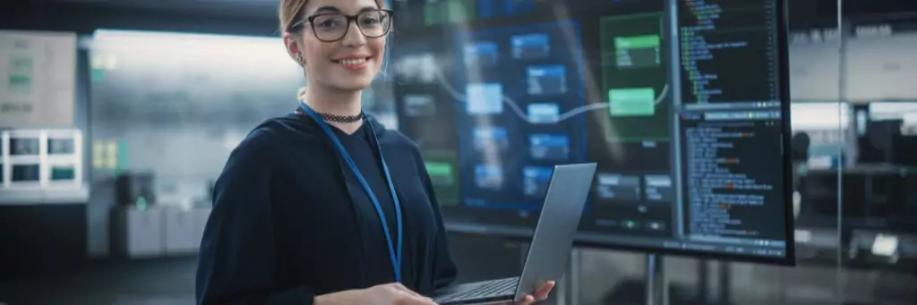 moça segurando notebook em sala de sistemas