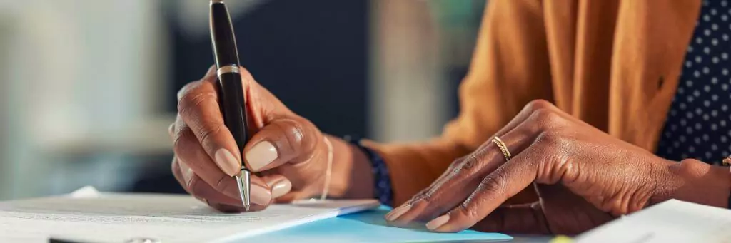 mulher assinando documento com caneta