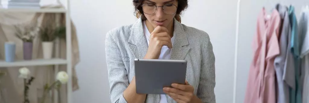 mulher olhando tablet em ateliê de roupas