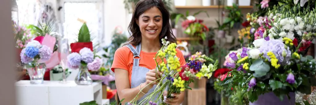mulher ajeitando flores em sua floricultura
