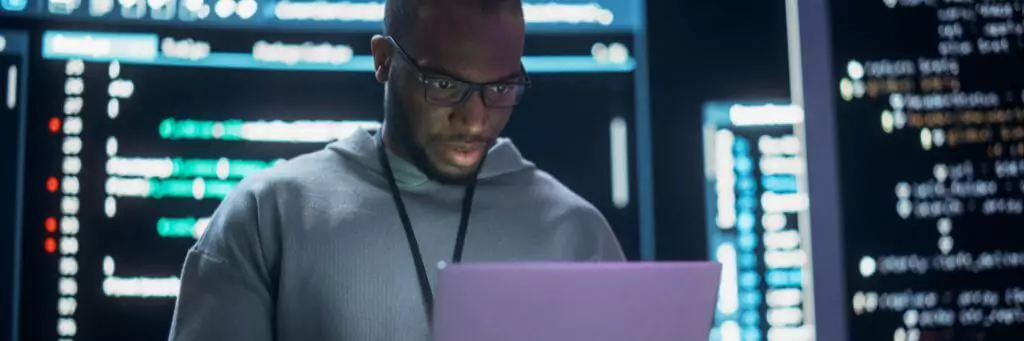 homem em central de servidores mexendo em computador