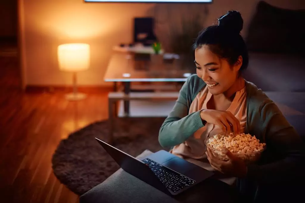 moça vendo algo em computador enquanto come pipoca