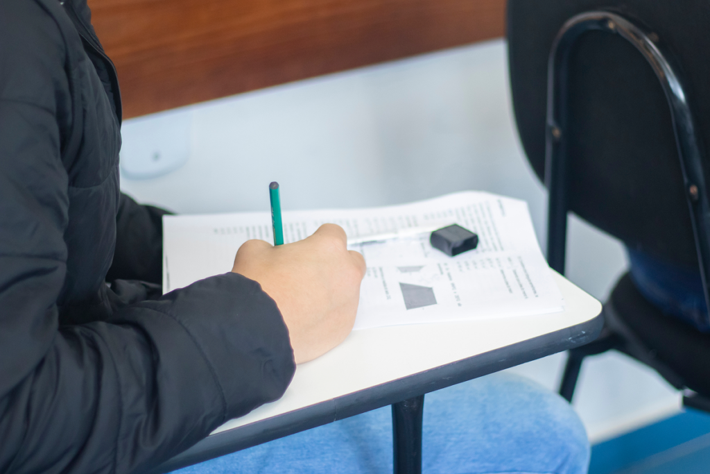Jovem fazendo prova em sala de aula.