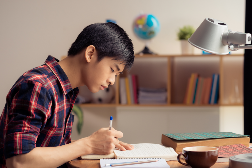 Jovem estudando em sua escrivaninha.